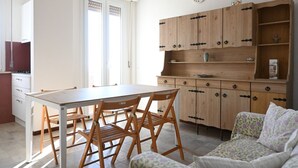 Una cocina con mesa y sillas, armarios de madera y un sofá.