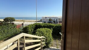 Vista desde una habitación con puerta de madera, una escalera y un estacionamiento con una tienda de campaña y coches.