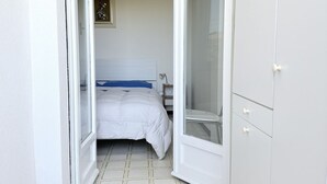 Un dormitorio con una cama, un armario blanco y una puerta que da a otra habitación.
