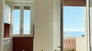 Una habitación con vista al mar, una mesa de comedor y una zona de cocina.