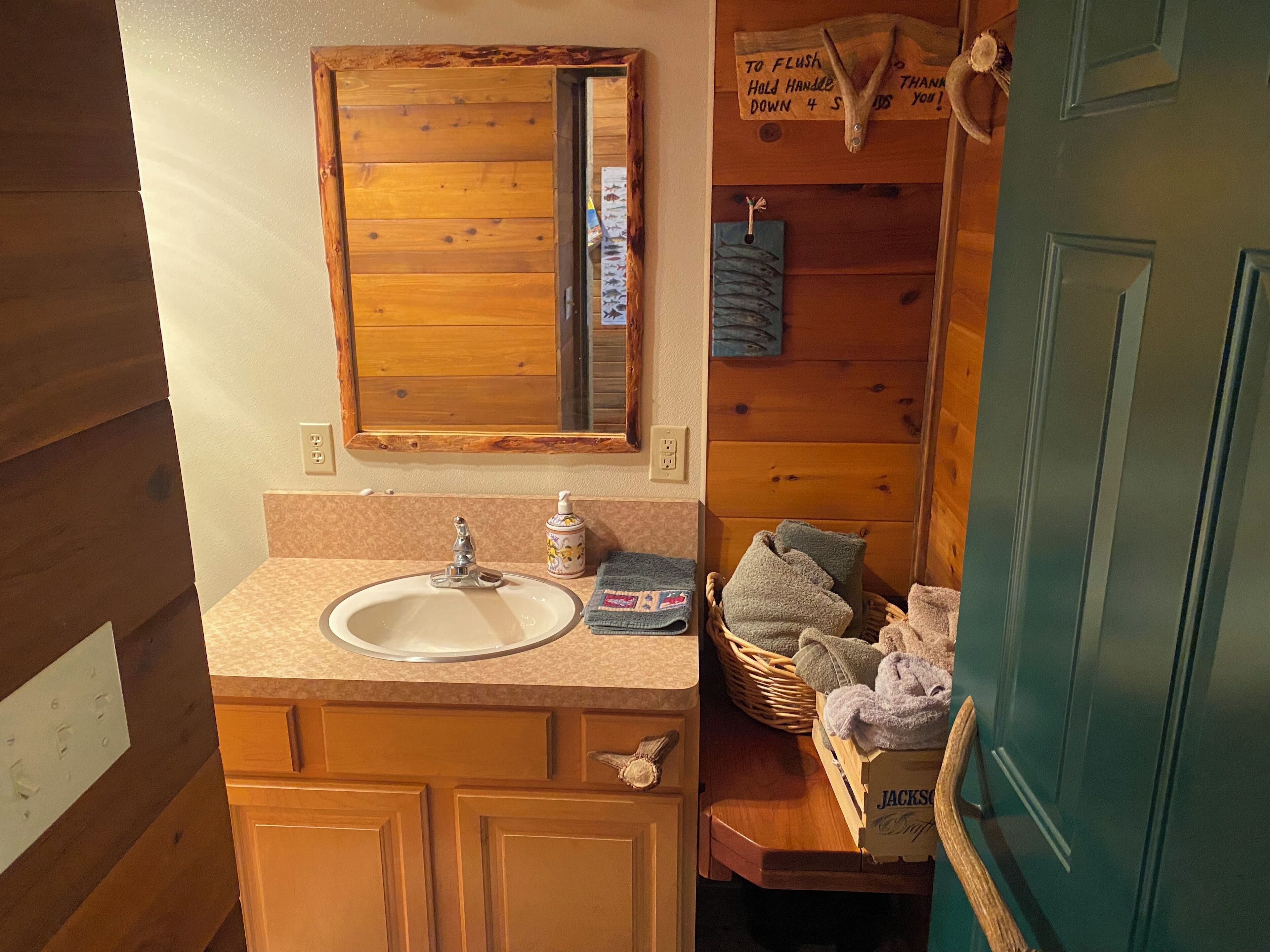 A bathroom with a wooden vanity, a sink, a mirror, and a towel rack.