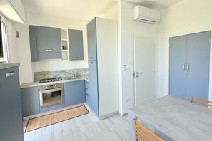 Eine moderne Küche mit grauen Schränken, einem eingebauten Backofen und einem Essbereich mit einem grauen Tisch.