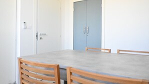 Une pièce avec une table et des chaises, une porte bleue et un mur blanc.