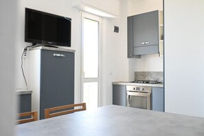 Une cuisine moderne équipée d’un téléviseur encastré, d’un réfrigérateur, d’une cuisinière et de placards.