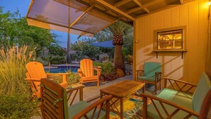 An outdoor patio with wooden chairs and a table, a pool, and a covered area with a view of the pool and garden. - Poolside Oasis, Luscious Gardens, and Spacious 4-bedroom house in Tucson (Tucson)