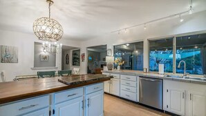 A modern kitchen with white cabinets, a wooden countertop, and a large window overlooking a garden. - Poolside Oasis, Luscious Gardens, and Spacious 4-bedroom house in Tucson (Tucson)