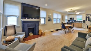 A spacious living room with a fireplace, a dining area, and a kitchen.