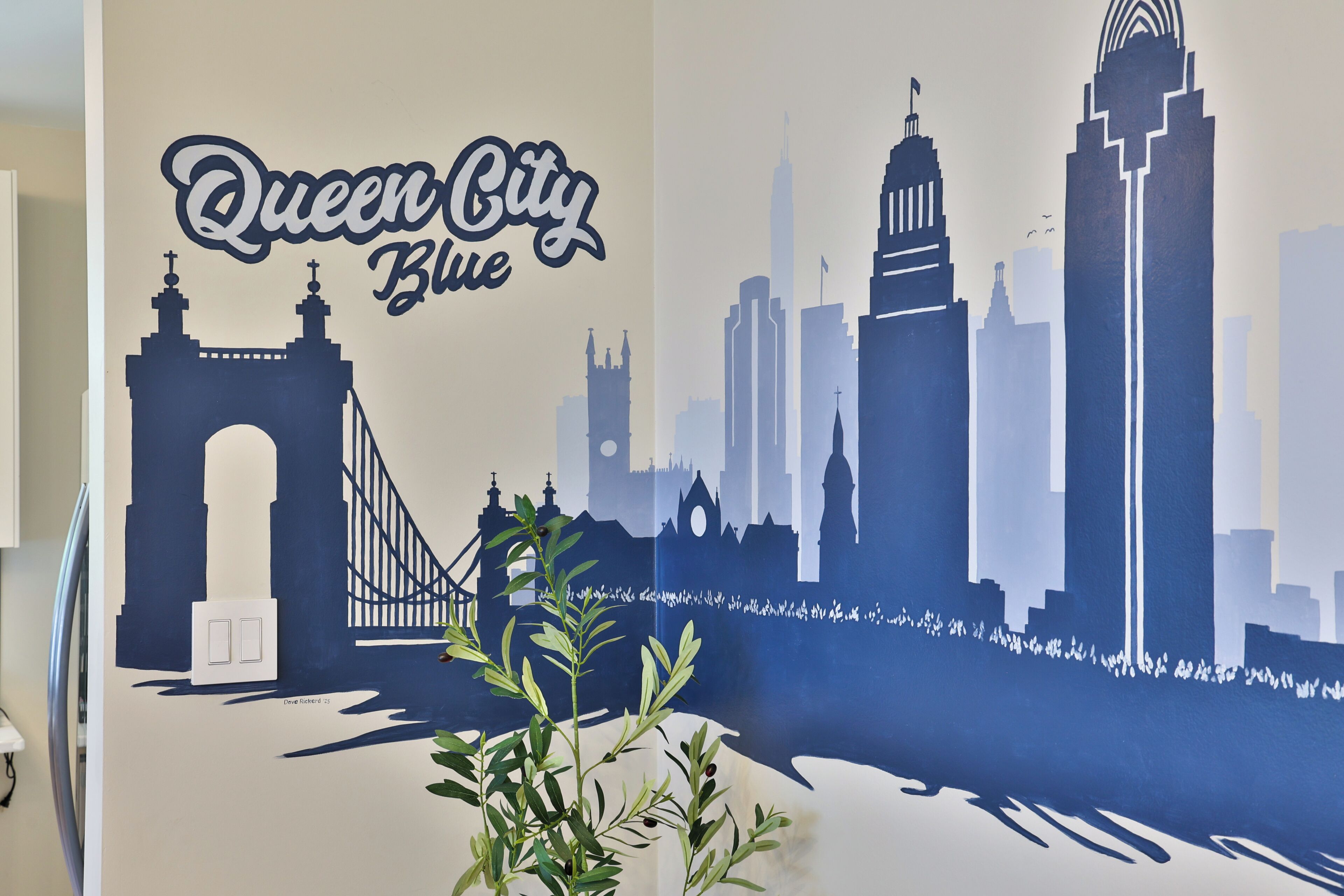 Un mural en la pared con el color Queen City Blue, un puente y el horizonte de la ciudad.