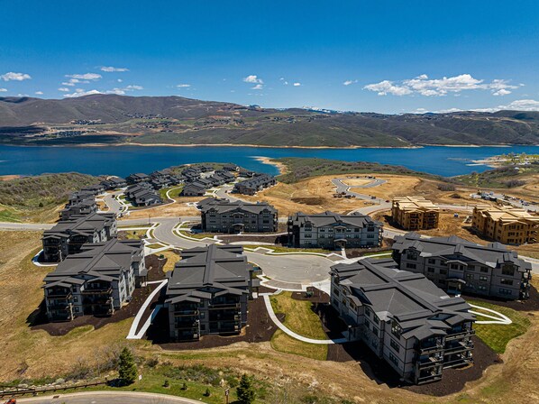A residential area with modern houses, a winding road, and a lake in the background.