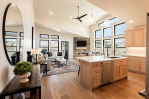 A spacious kitchen with a large island, wooden cabinets, and a modern ceiling fan.