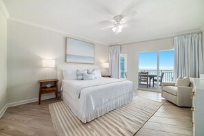 Ein Schlafzimmer mit Bett, Nachttischen, Deckenventilator und Meerblick vom Balkon aus.