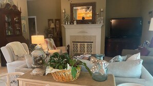 A living room with a fireplace, a television, and various decorative items.