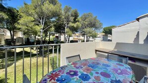 Une terrasse agrémentée d’une nappe à motifs floraux aux couleurs vives, d’une rambarde en métal et offrant une vue sur un quartier résidentiel avec des arbres et des immeubles.