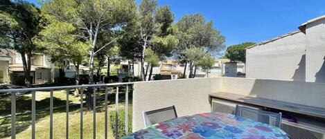 Relax on the balcony overlooking a serene garden with a table for two.