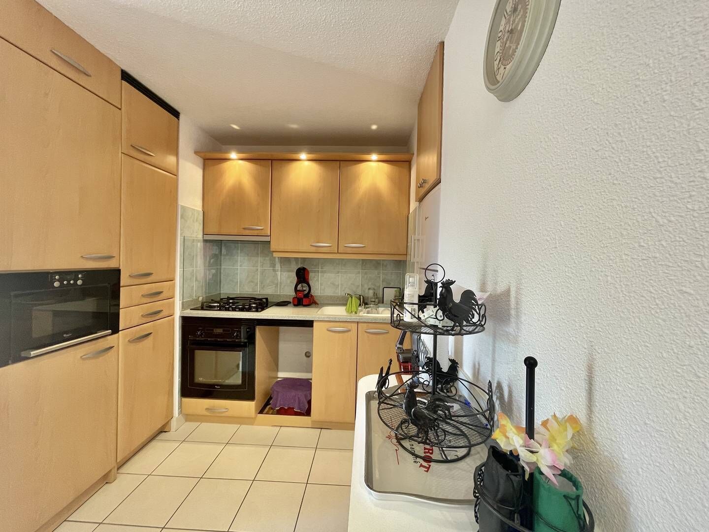 Une cuisine compacte avec des meubles en bois, un four encastré, une cuisinière à gaz et une machine à café.