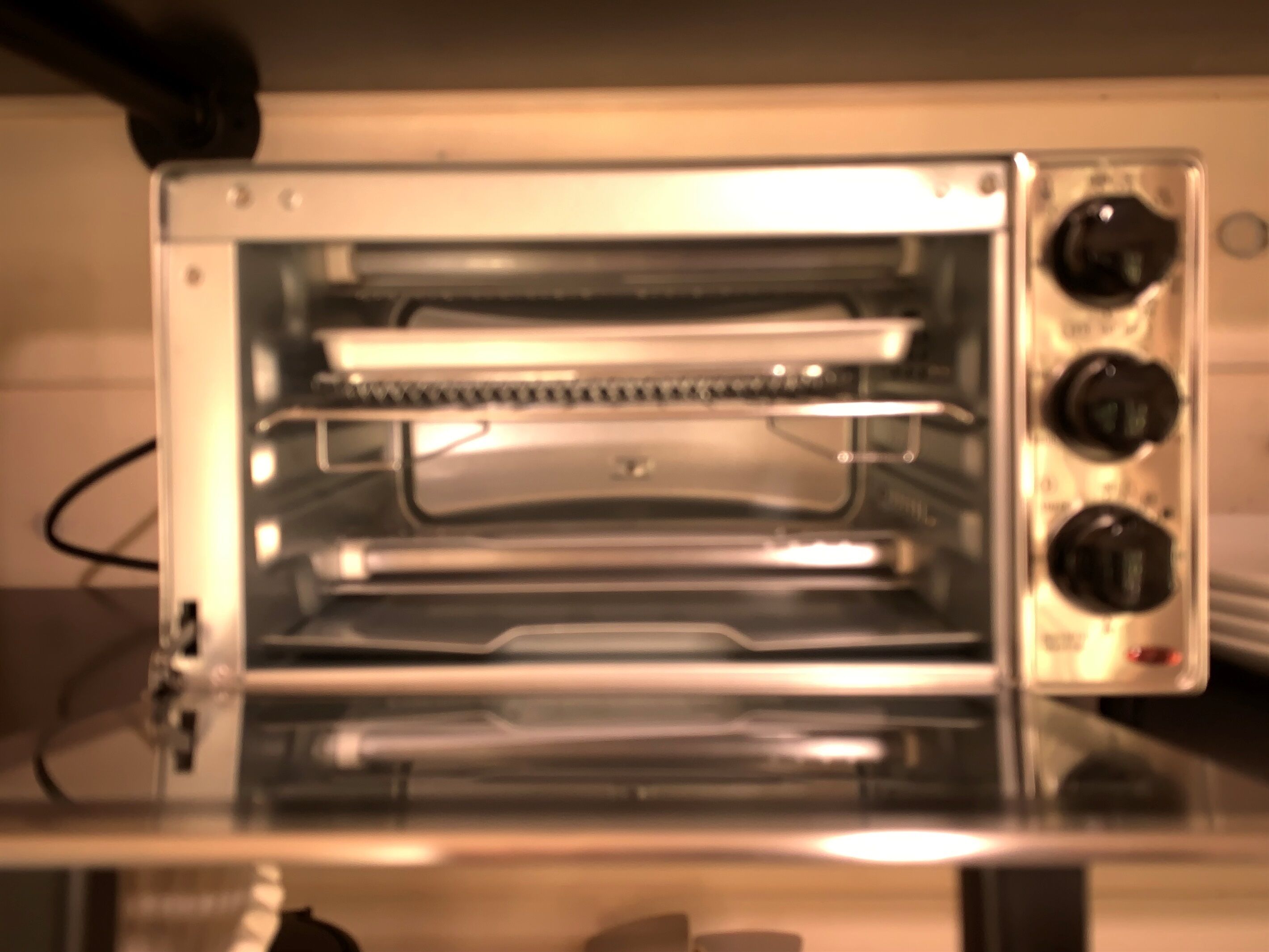 A small, clear-fronted toaster oven with a control panel on the right side.