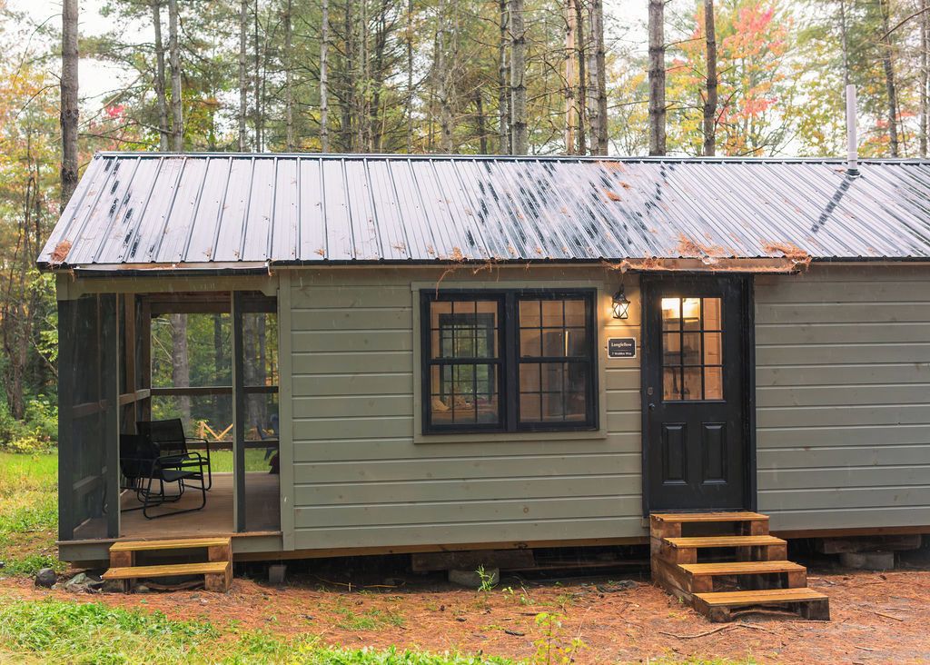 A rustic cabin with a porch, a door, and a window.