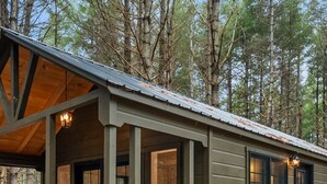 A cabin with a covered porch, large windows, and a wooden deck.