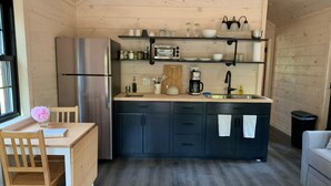 A compact kitchen with dark cabinets, a stainless steel refrigerator, a coffee maker, and a sink.