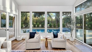A spacious room with two sofas facing a large window overlooking a swimming pool. - 6 Wood Duck Court at The Sea Pines Resort (Hilton Head Island)