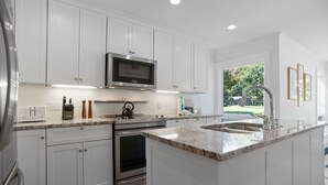 A modern kitchen with white cabinetry, stainless steel appliances, a built-in microwave, and a large island with a sink. - 173 Twin Oaks at The Sea Pines Resort (Hilton Head Island)