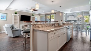 A modern kitchen with a large island, bar stools, and a ceiling fan. - 1266 Harbour Town Club at The Sea Pines Resort (Hilton Head Island)