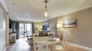 A dining area with a round table and chairs, a chandelier, and a painting on the wall.
