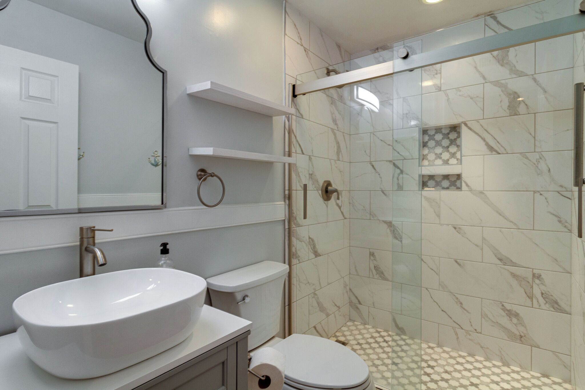 Une salle de bain moderne avec un grand lavabo blanc, des toilettes et une douche séparée par une paroi en verre.
