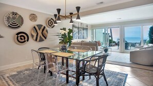 Un comedor moderno con una mesa de vidrio, sillas transparentes y un jarrón central.