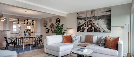 Una sala de estar moderna con sofá blanco, mesa de centro y comedor.