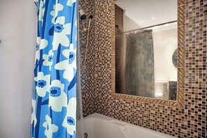 A bathroom with a shower, a bathtub, and a mirror with a mosaic tile border. - 738 Schooner Court at The Sea Pines Resort (Hilton Head Island)