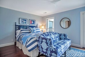 A bedroom with a bed, a blue and white patterned sofa, a lamp, and two framed pictures on the wall. - 738 Schooner Court at The Sea Pines Resort (Hilton Head Island)