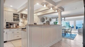 Una cocina amplia con armarios blancos, una isla central y un comedor con vistas.