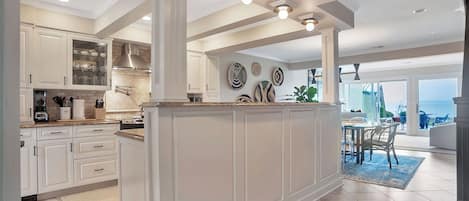A spacious kitchen with white cabinetry, a central island, and a dining area with a view.