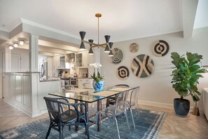 A modern kitchen with white cabinets, a glass dining table, and a chandelier. - 738 Schooner Court at The Sea Pines Resort (Hilton Head Island)