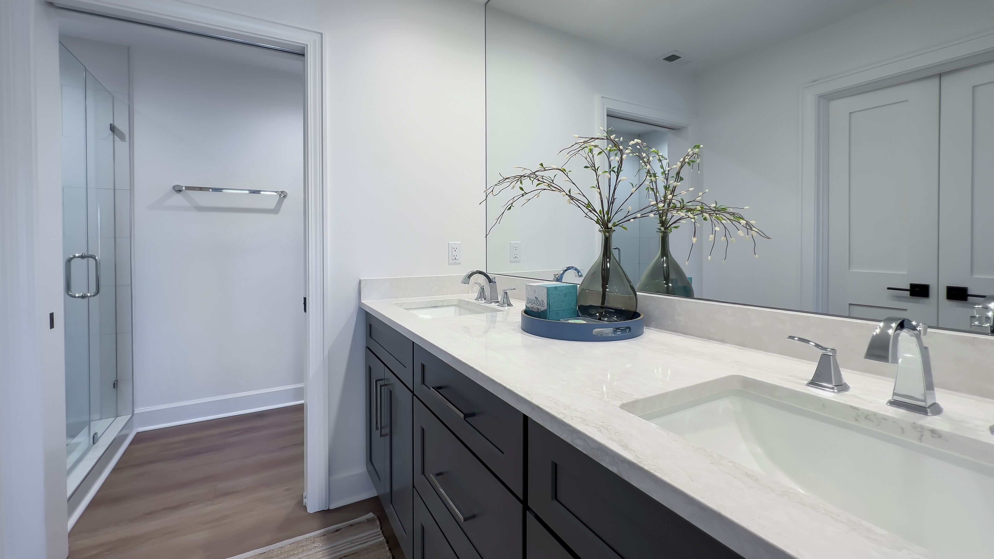 A modern bathroom with a large white sink, a mirror, and a glass shower enclosure.