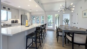 A modern kitchen with a large island, stainless steel appliances, and a dining area with a long table and chairs.