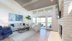 A spacious living room with a sofa, armchairs, a coffee table, and a fireplace.