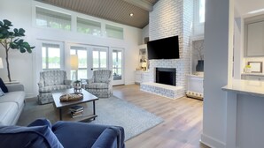 A spacious living room with a fireplace, comfortable seating, and large windows.