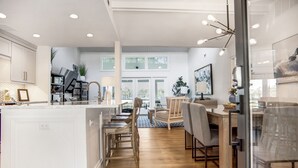 Una cocina amplia con una isla central, piso de madera y luminarias modernas.