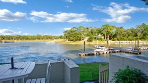 A lakeside view with docked boats, a grassy area, and a building with a sloped roof.