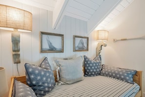 A bedroom with a bed, two wall-mounted lamps, and two framed pictures of sailboats. - 1605 Port Villas at The Sea Pines Resort (Hilton Head Island)