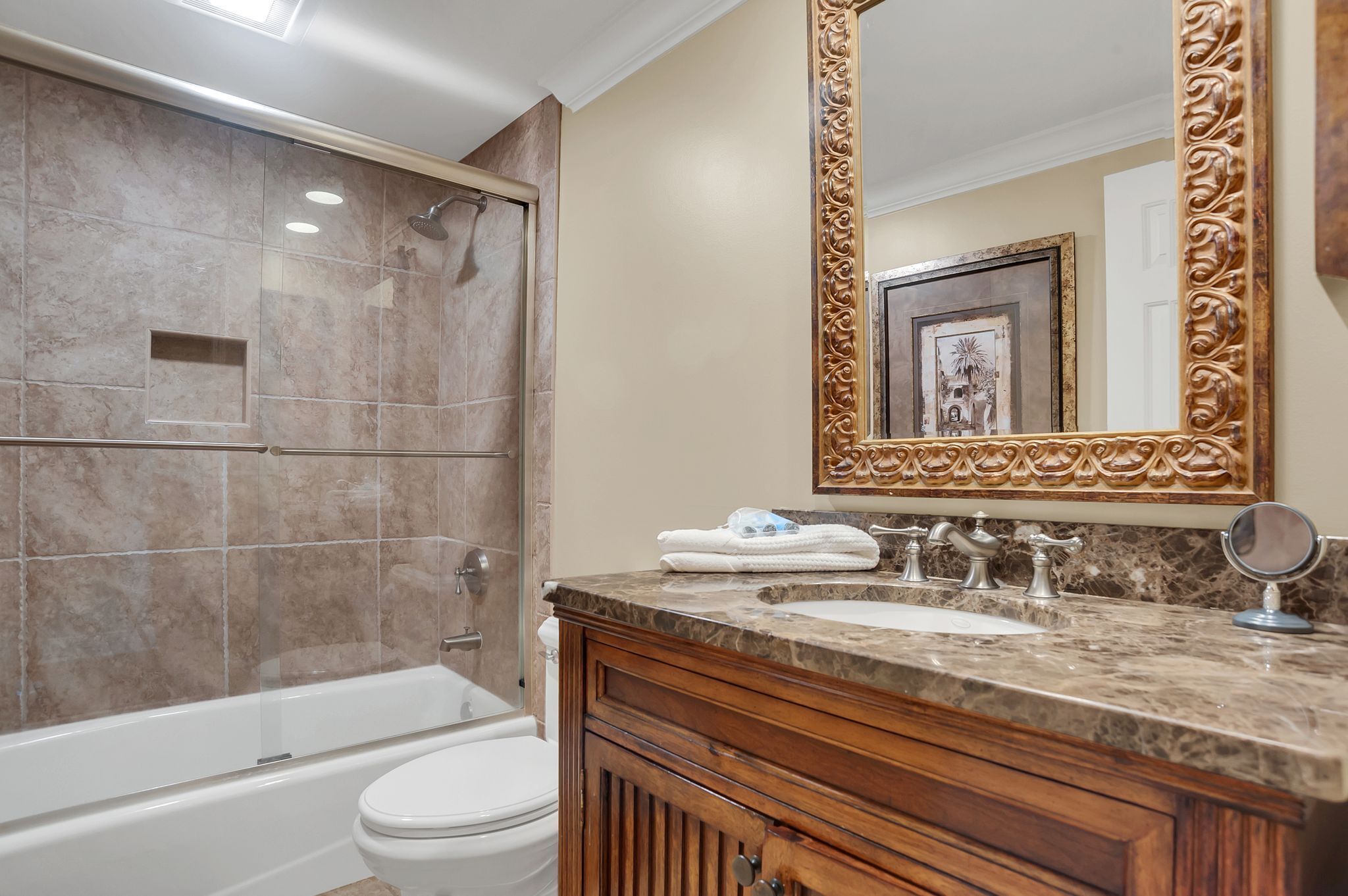 A bathroom with a bathtub, toilet, vanity with a sink, and a large mirror.