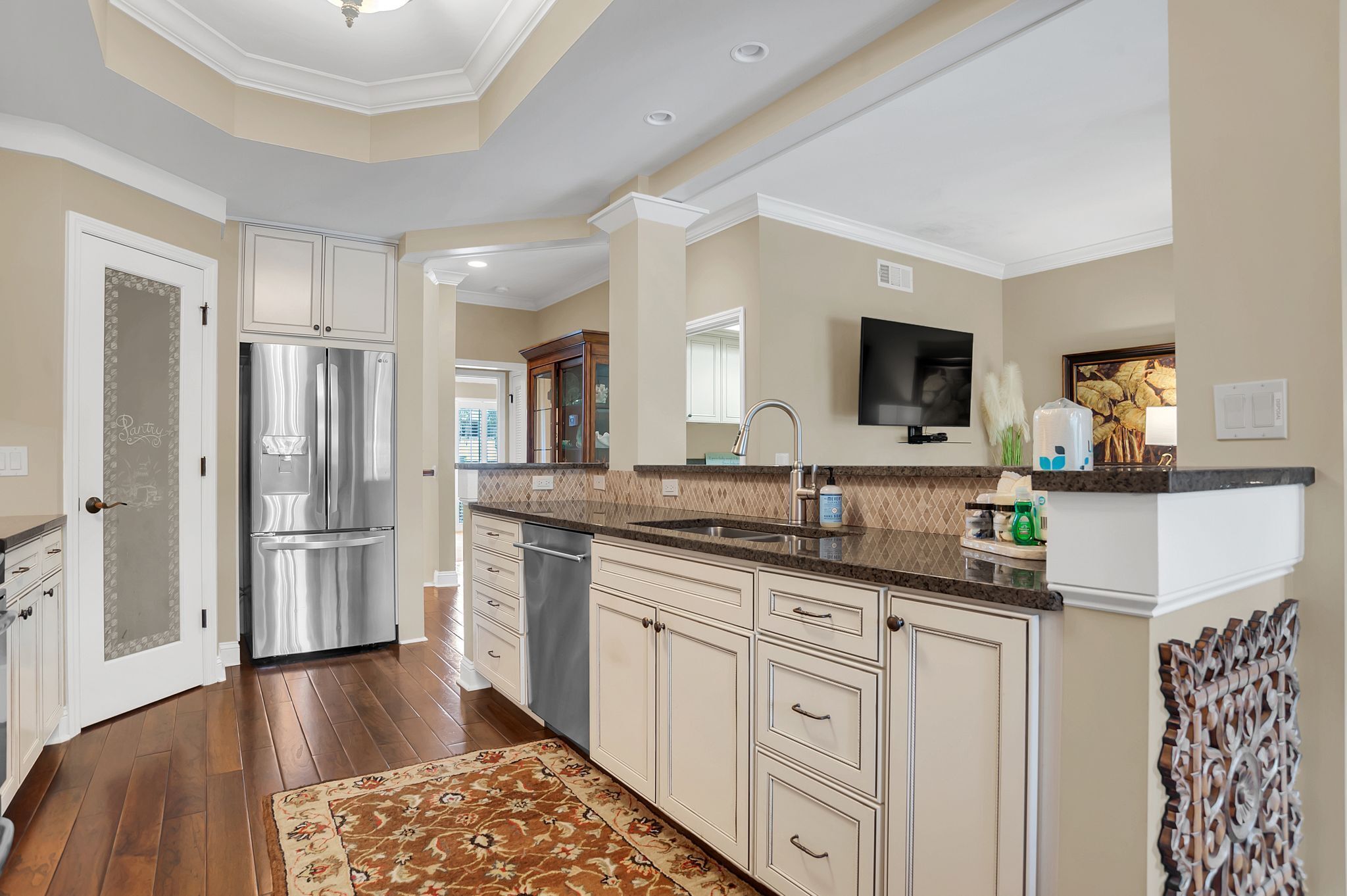 A modern kitchen with a stainless steel refrigerator, white cabinetry, and a granite countertop.