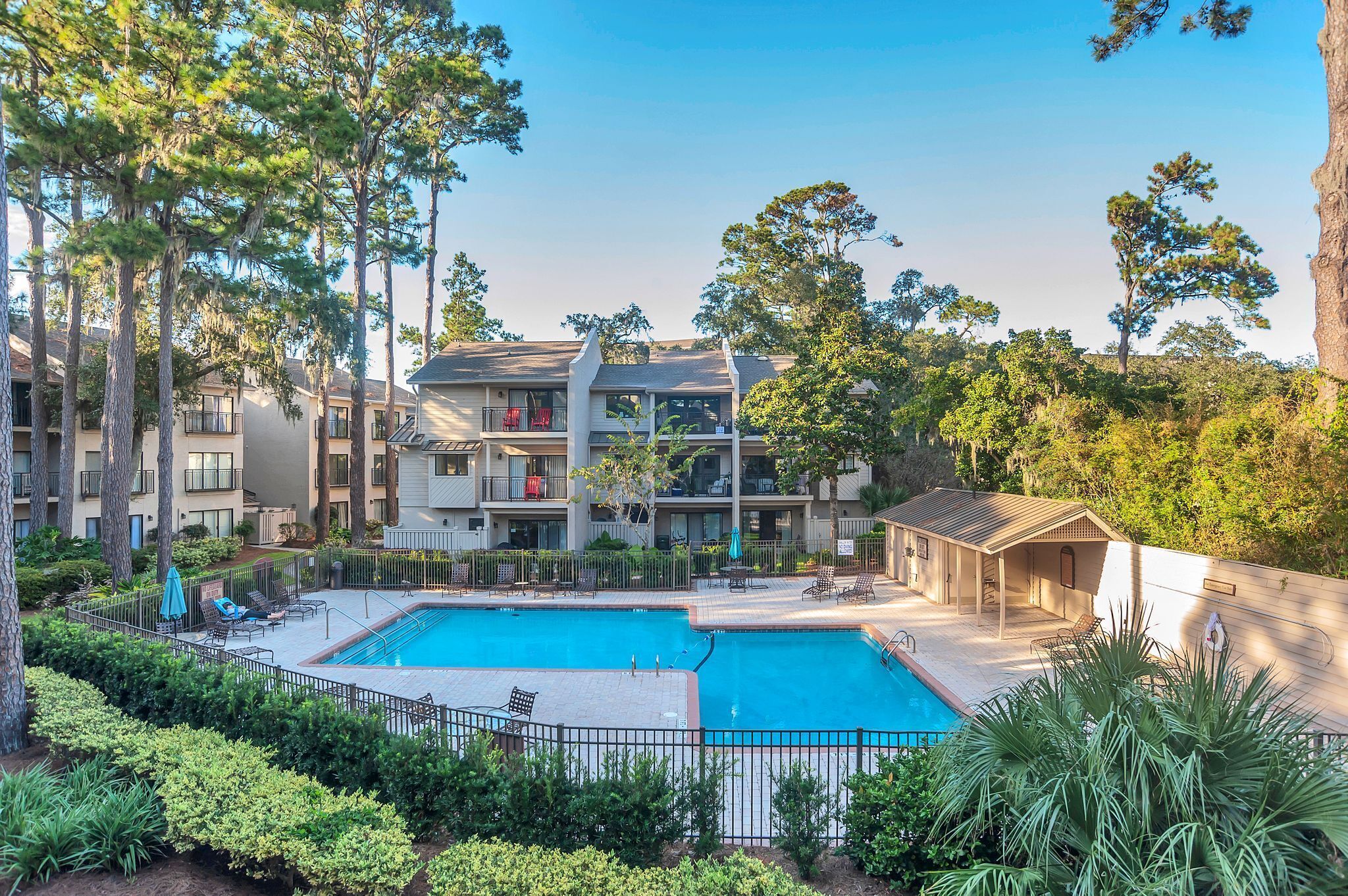 A multi-story residential building with a swimming pool, surrounded by trees and greenery.