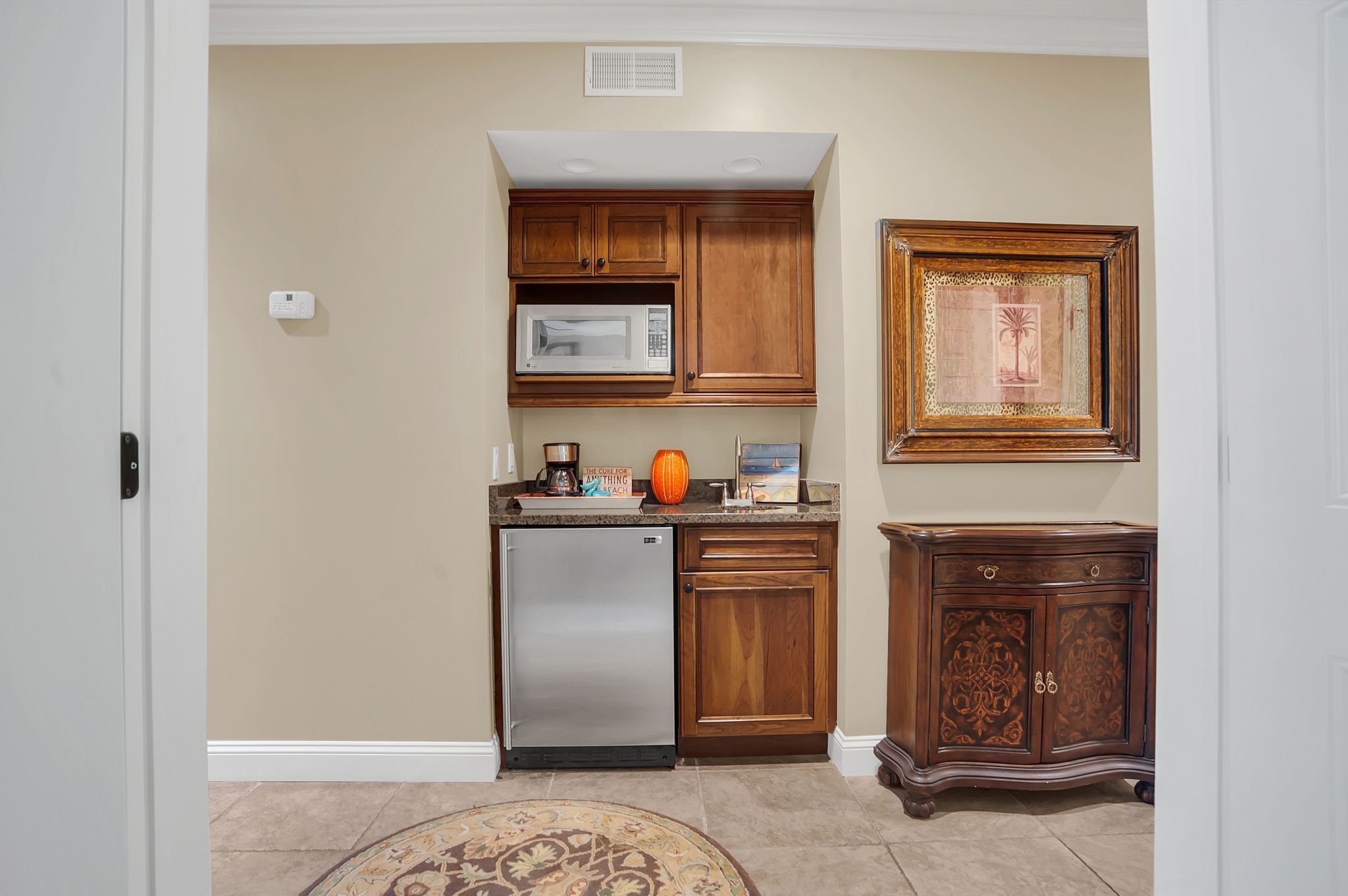 Una cocina con armarios de madera, un refrigerador de acero inoxidable, un microondas y un adorno en la pared.