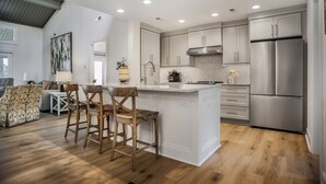 A modern kitchen with white cabinetry, a stainless steel refrigerator, and a wooden island with bar stools. - 6954 Fairway One at The Sea Pines Resort (Hilton Head Island)