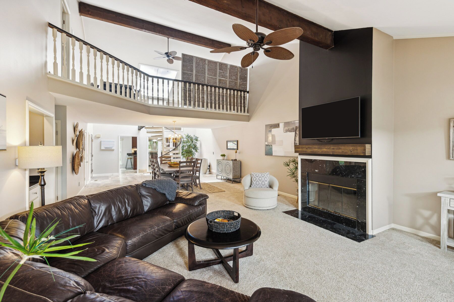 A spacious living area with a leather sofa, a dining table, and a fireplace.