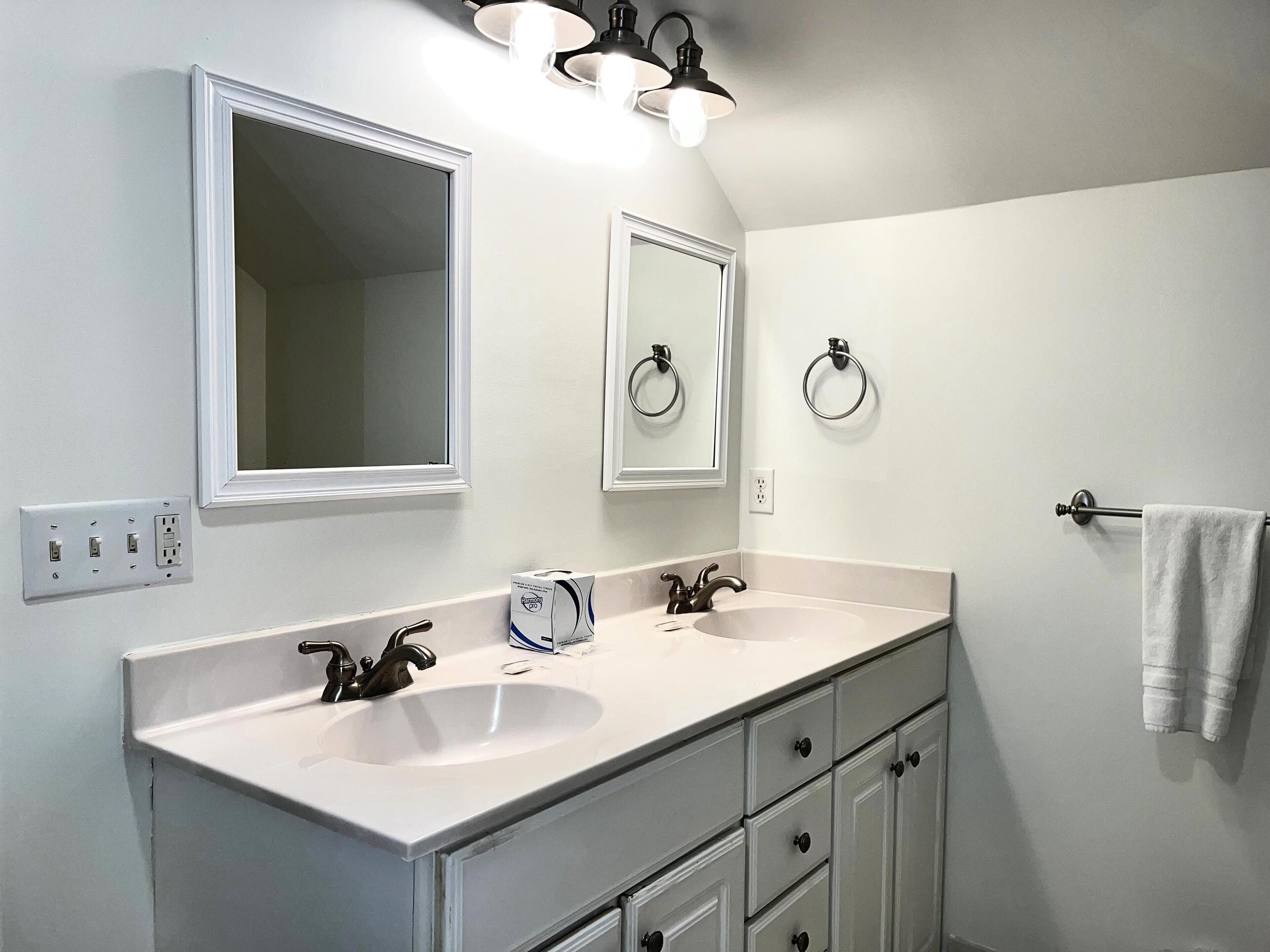 A bathroom with two sinks, a mirror, and a towel rack.