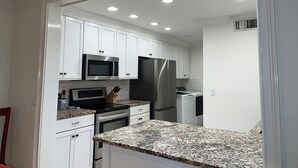 A modern kitchen with white cabinets, stainless steel appliances, granite countertops, and recessed ceiling lighting. - 2251 Heritage Villas at The Sea Pines Resort (Hilton Head Island)